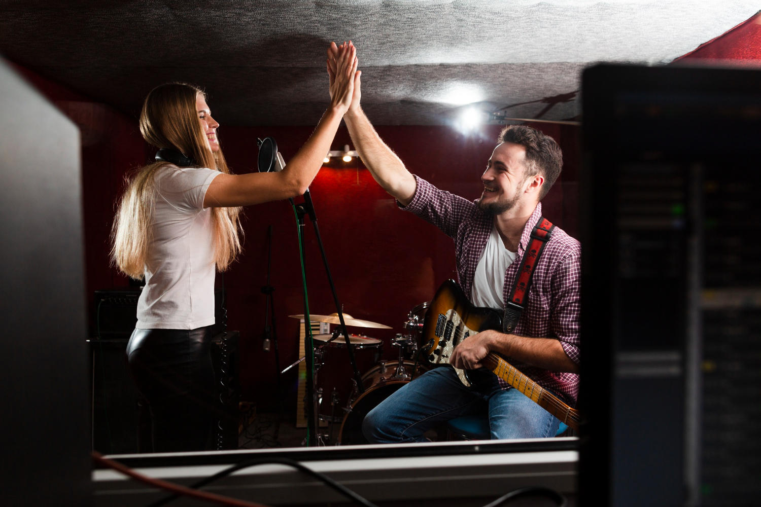 Man and woman in a music studio high-fiving.