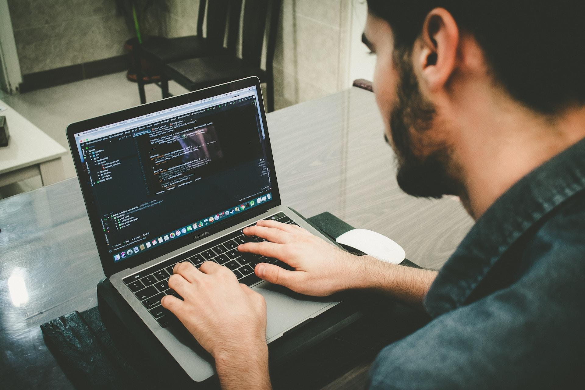 A man programming on a laptop.