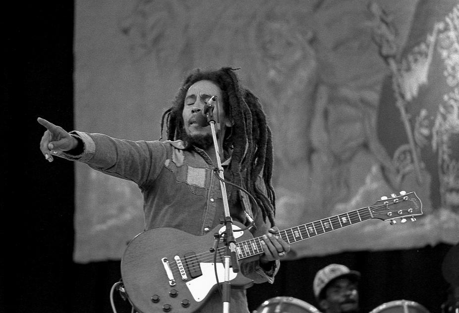 Bob Marley playing guitar and singing on stage