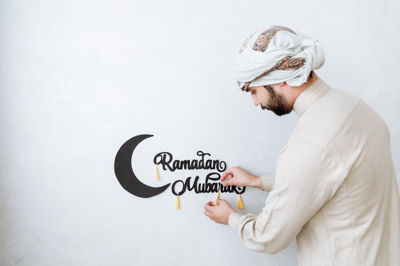 a man hanging a ramadan decoration on the wall 
