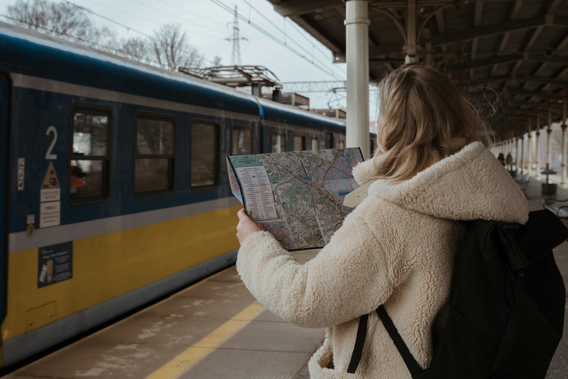 A girl with a map at a train station.