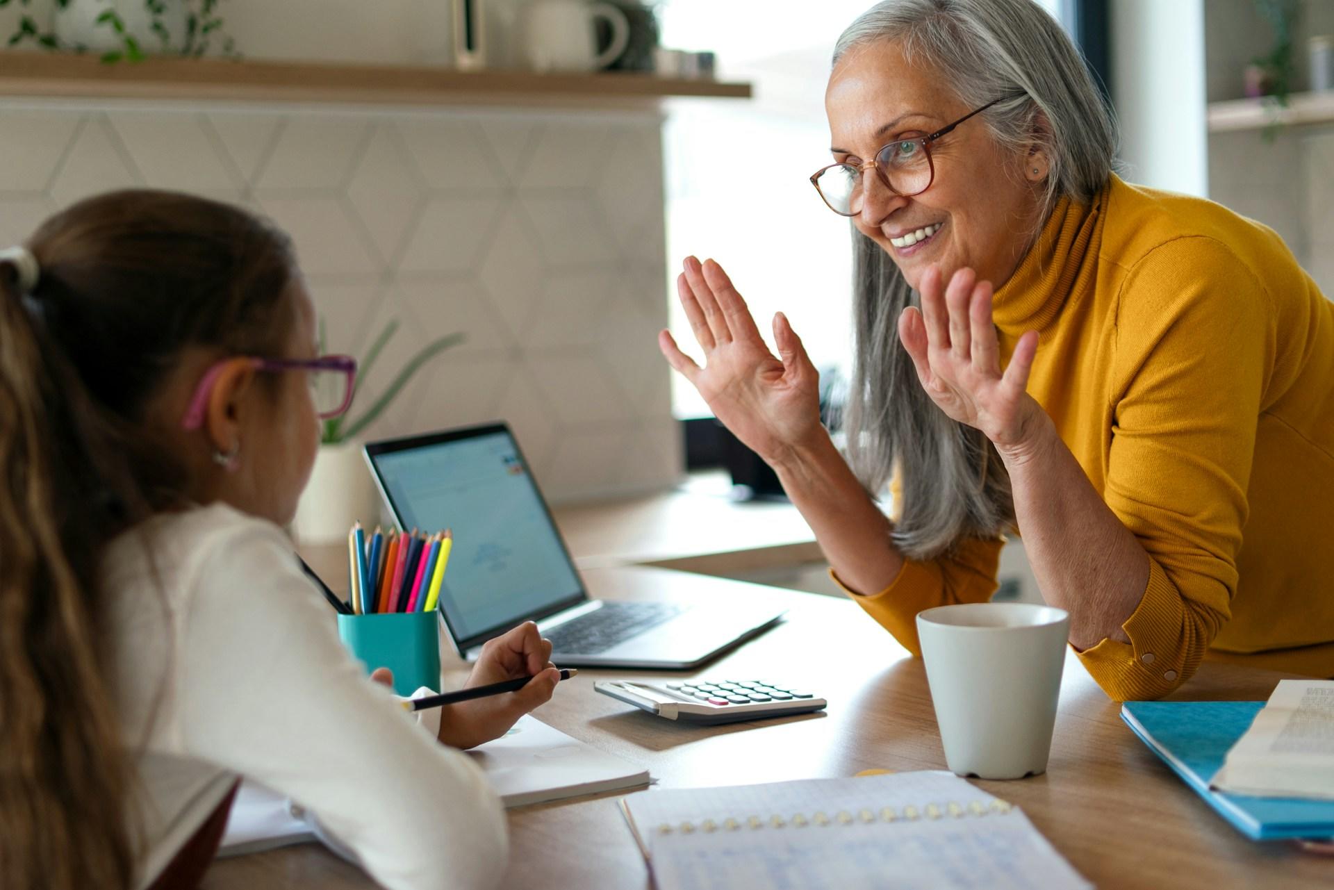 an older woman and a young girl working together on a desk
