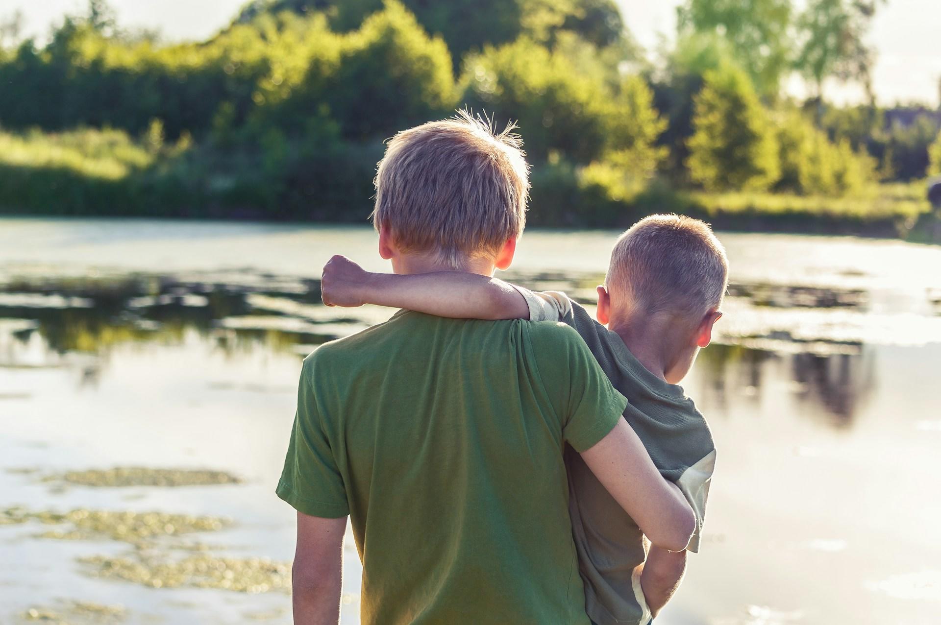 Two children holding each other, overlooking a nature scene.