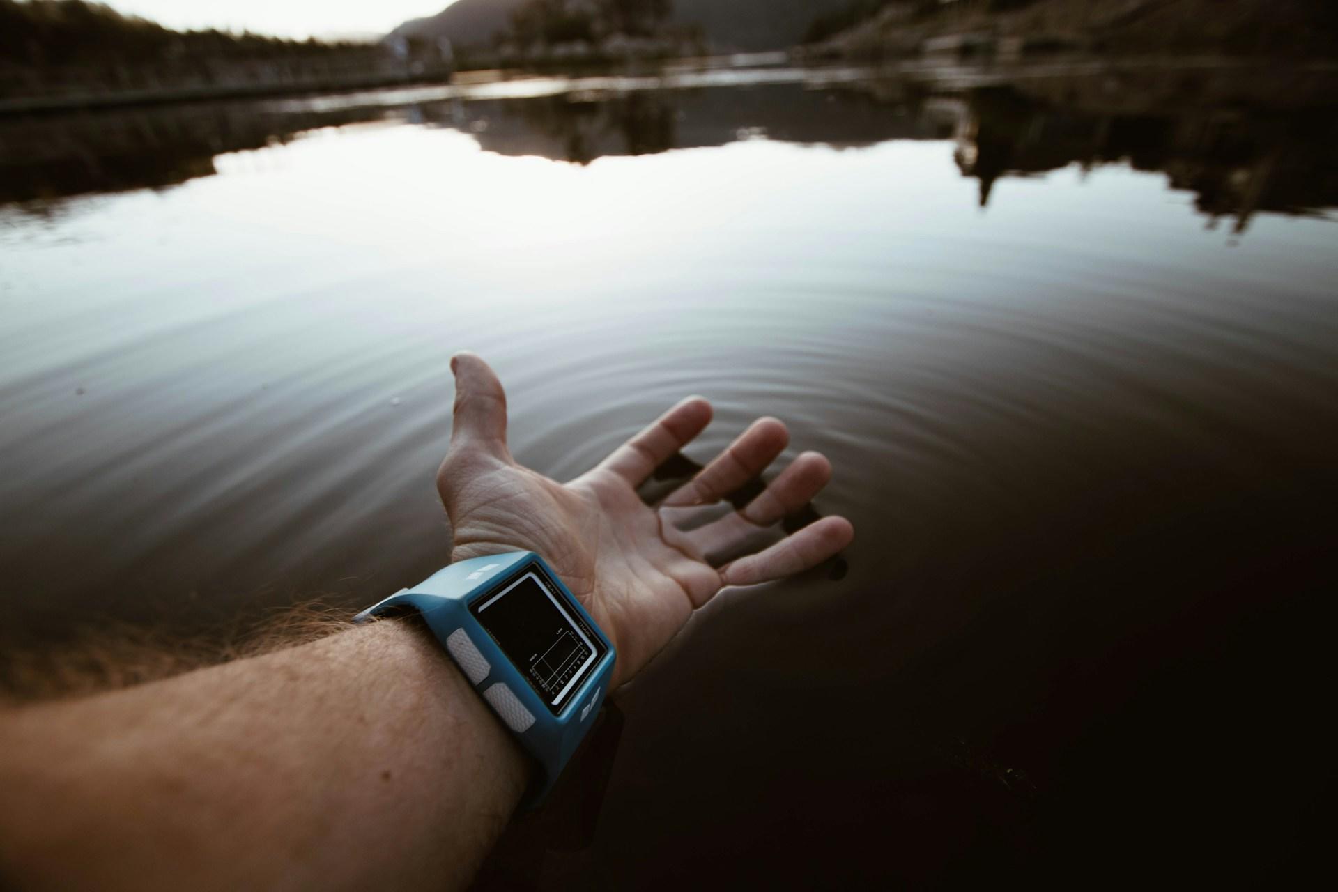 An outstretched arm with a watch over a lake.