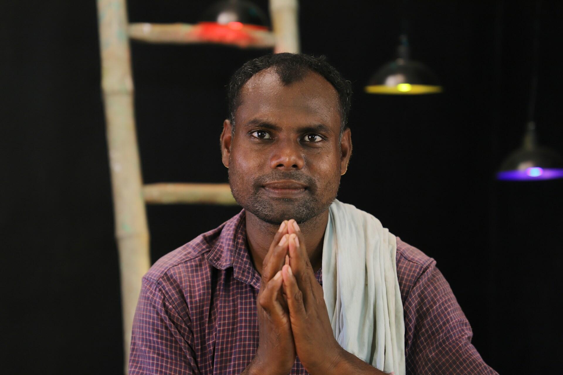 An Indian man doing the Namaste pose.