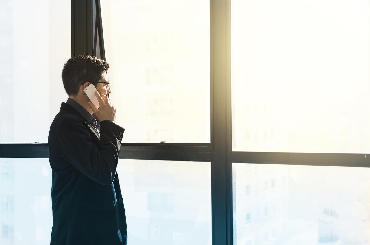 man talking on a telephone in front of a window