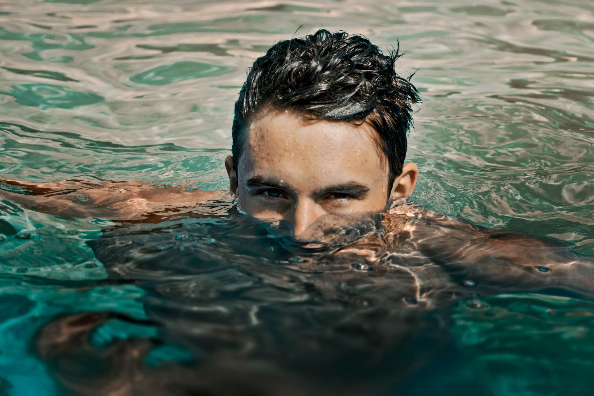 A man with his head half-submerged while swimming.