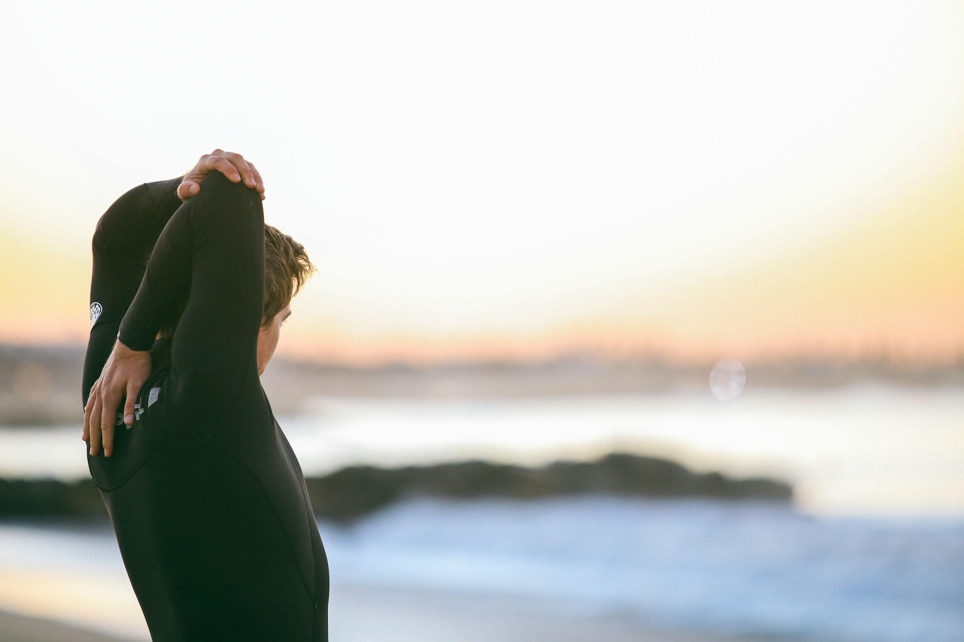 A man in a wetsuit getting ready to swim or surf.