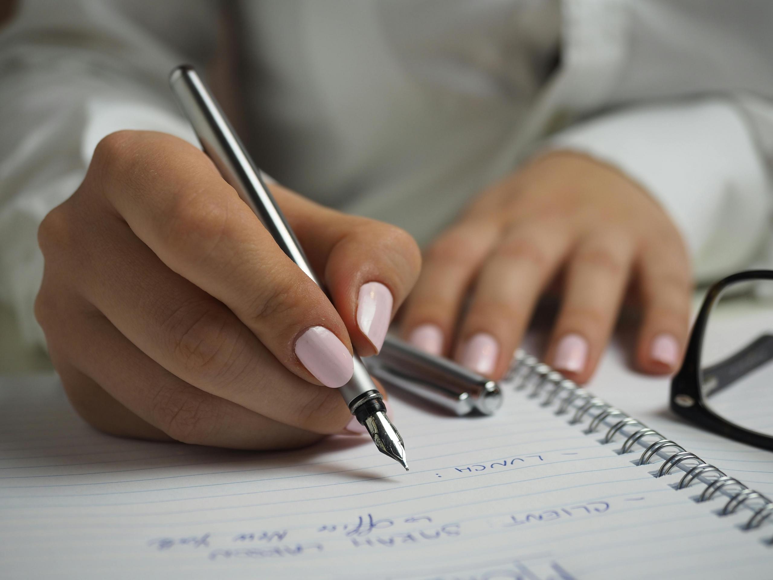 a woman writes in a notebook.