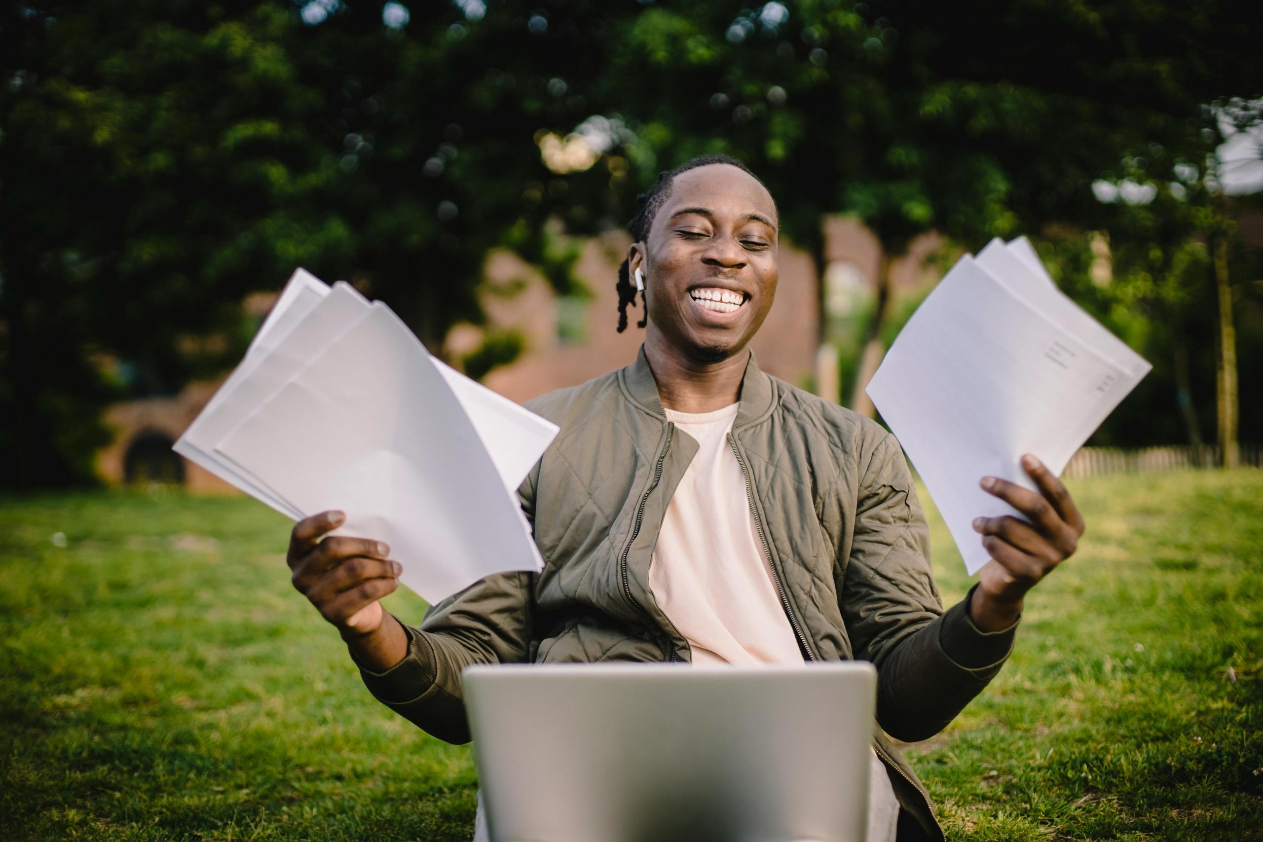 a man holds papers in front of a computer.