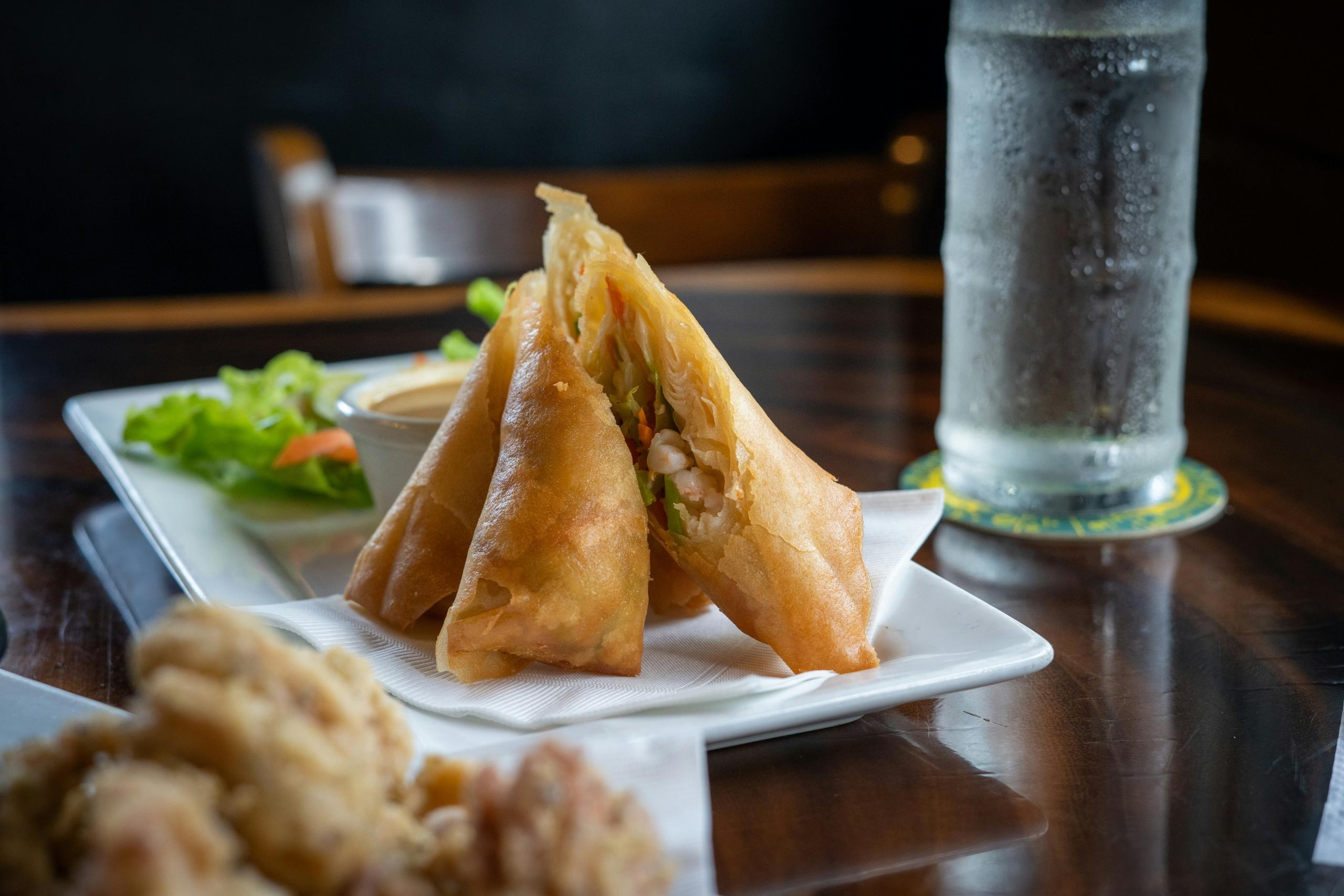 A plate of spring rolls stacked in a pyramid shape.