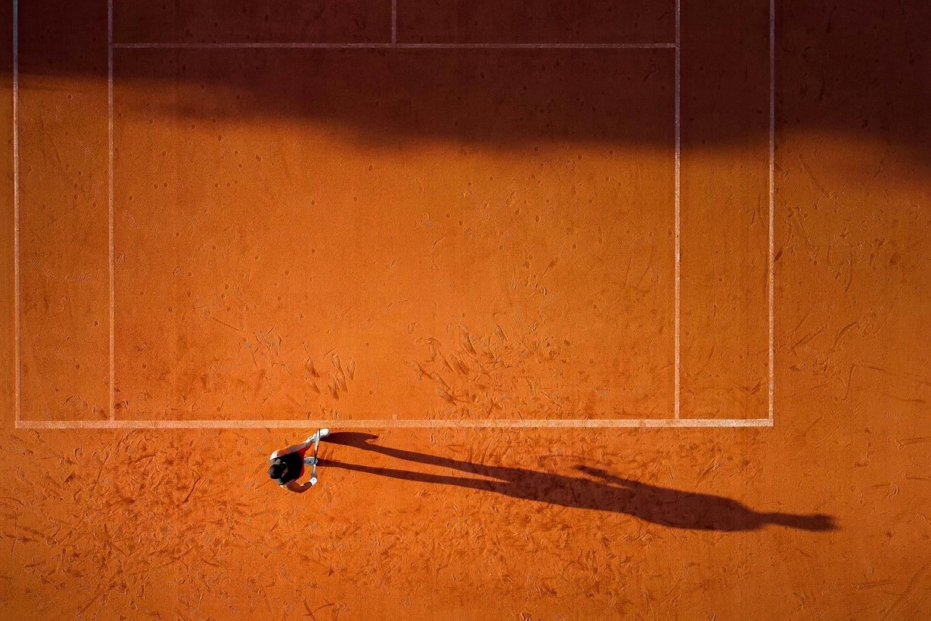 A tennis player serving on a clay court.