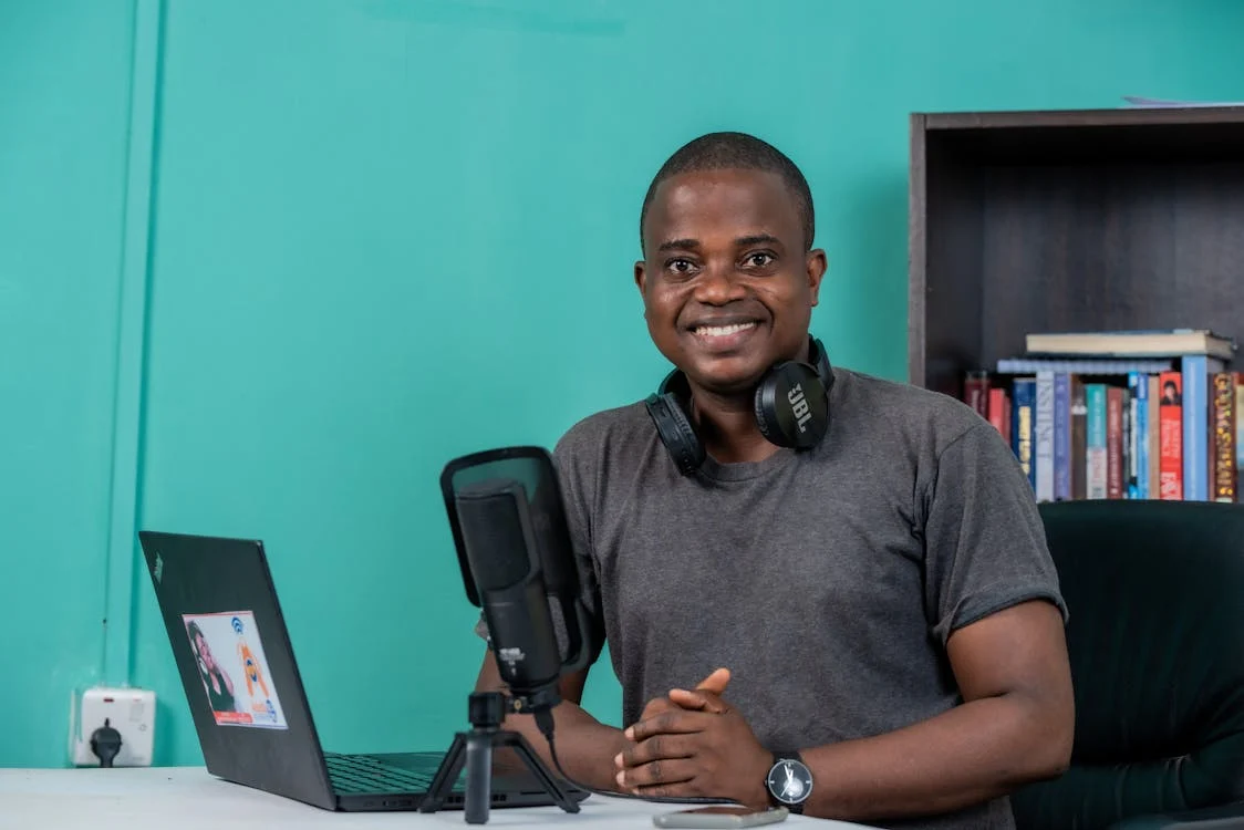 A Black man sitting at a desk in a recording studio.