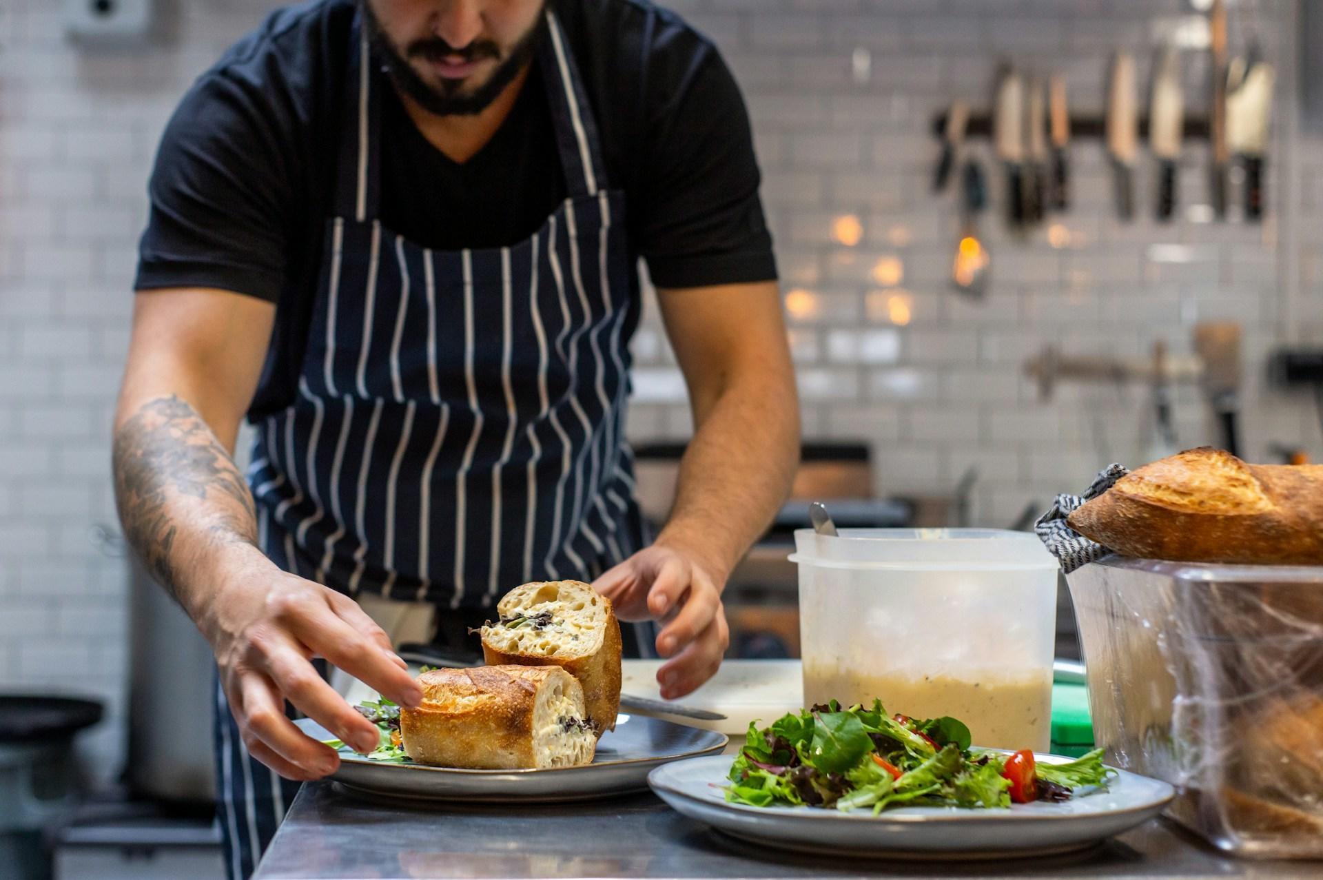 A chef preparing a two sandwiches in a plate after preparing a salad.
