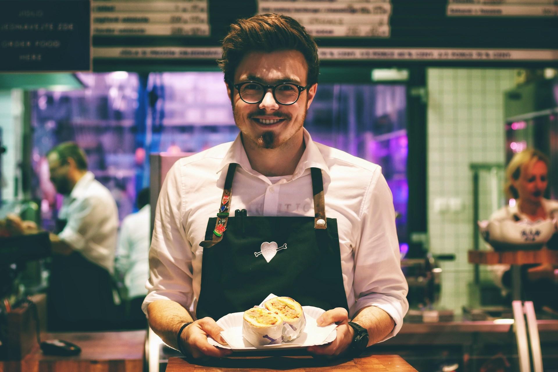 A chef showing the meal he prepared to the camera with a smile.