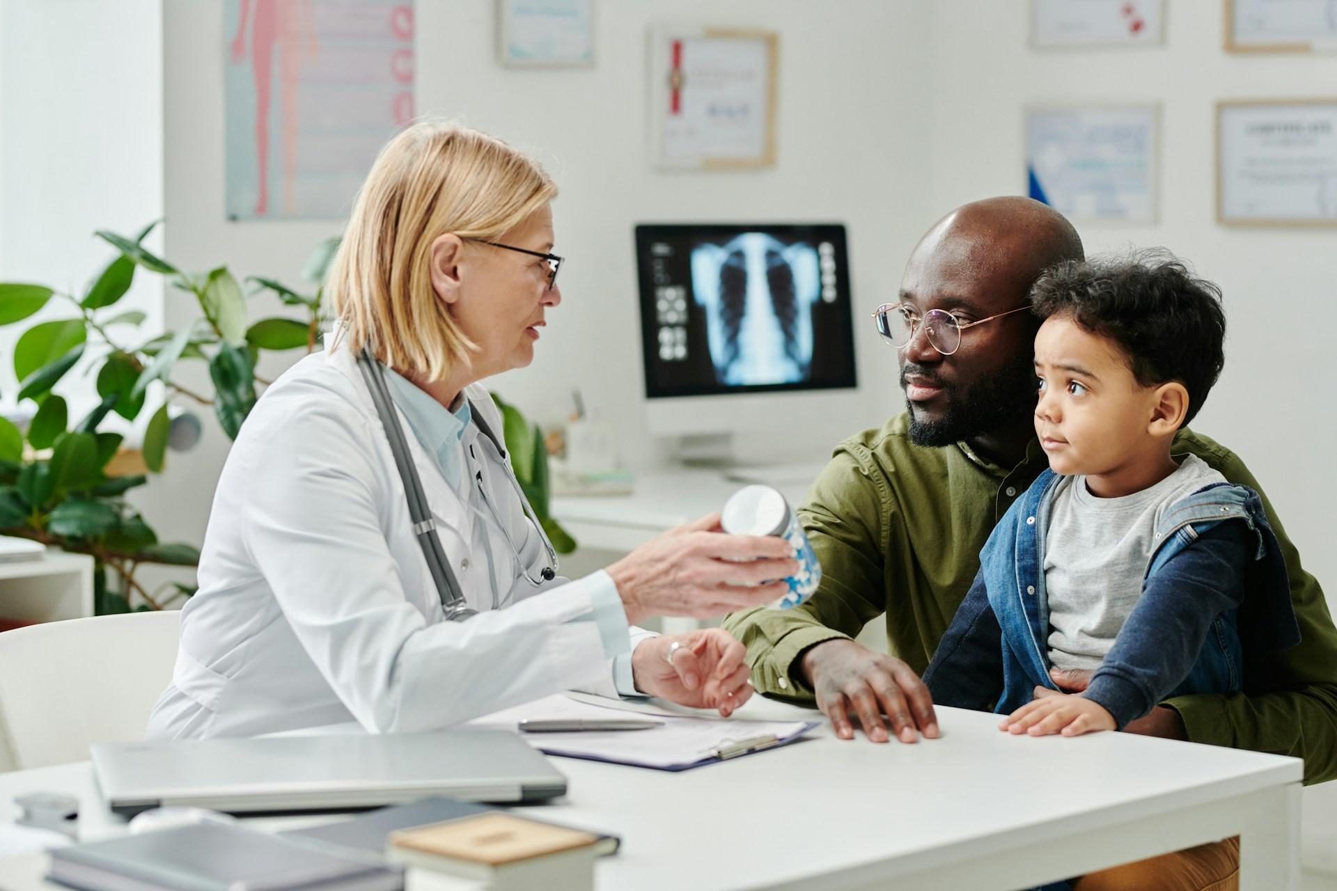 female doctor speaking to a child and his father