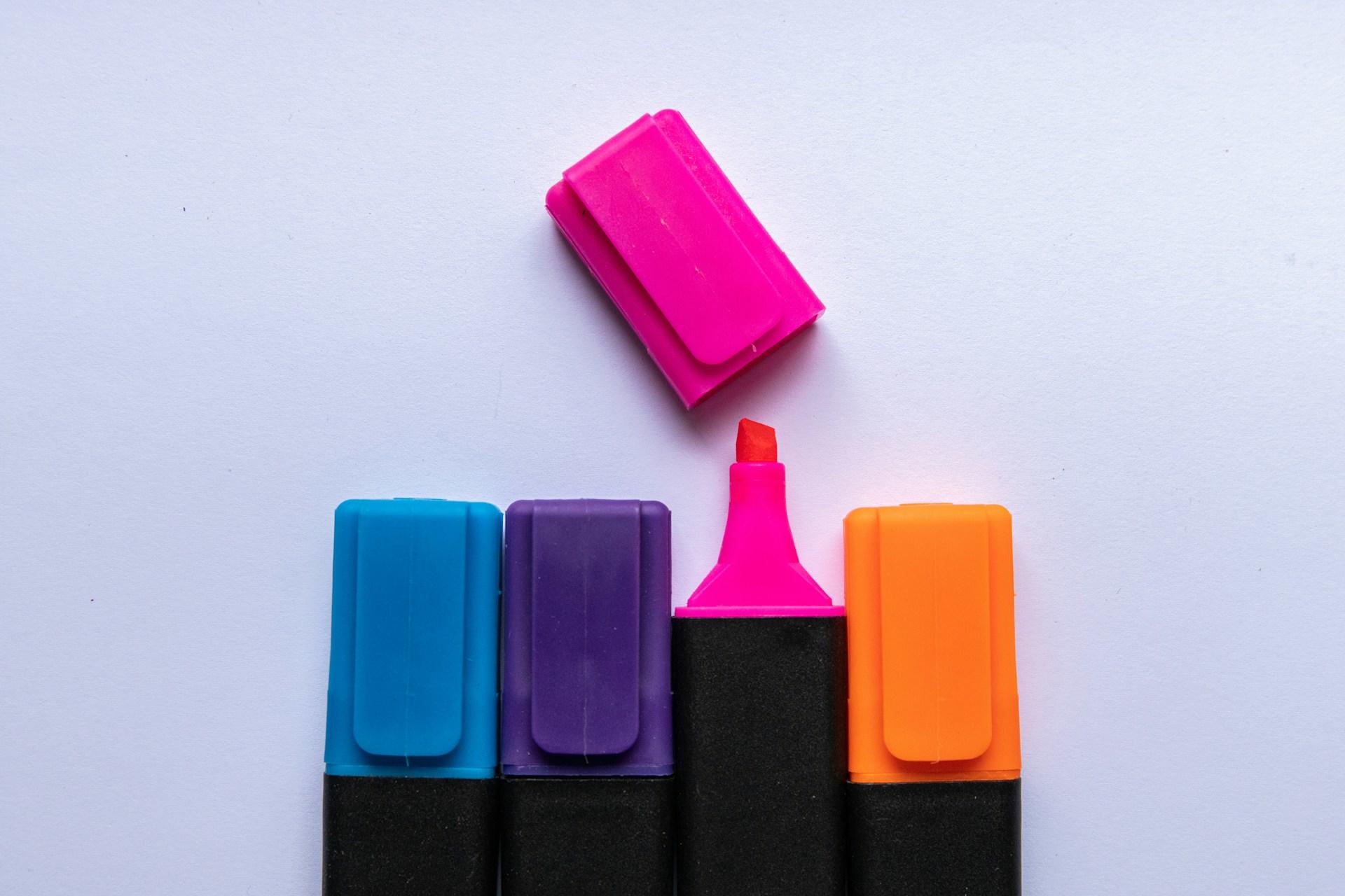 Four highlighter pens with one with the cap removed.
