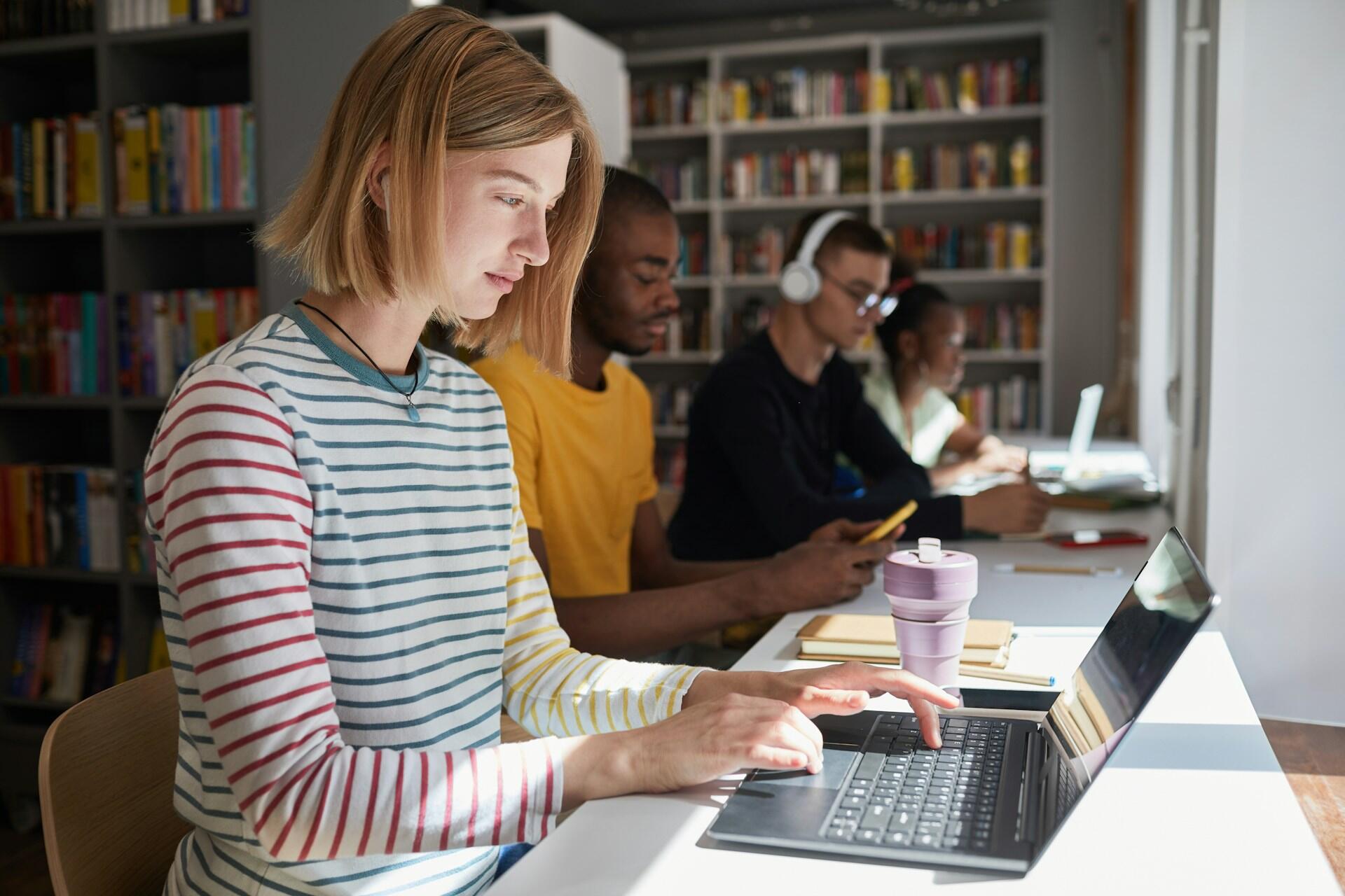 People sitting at a table in a library. 