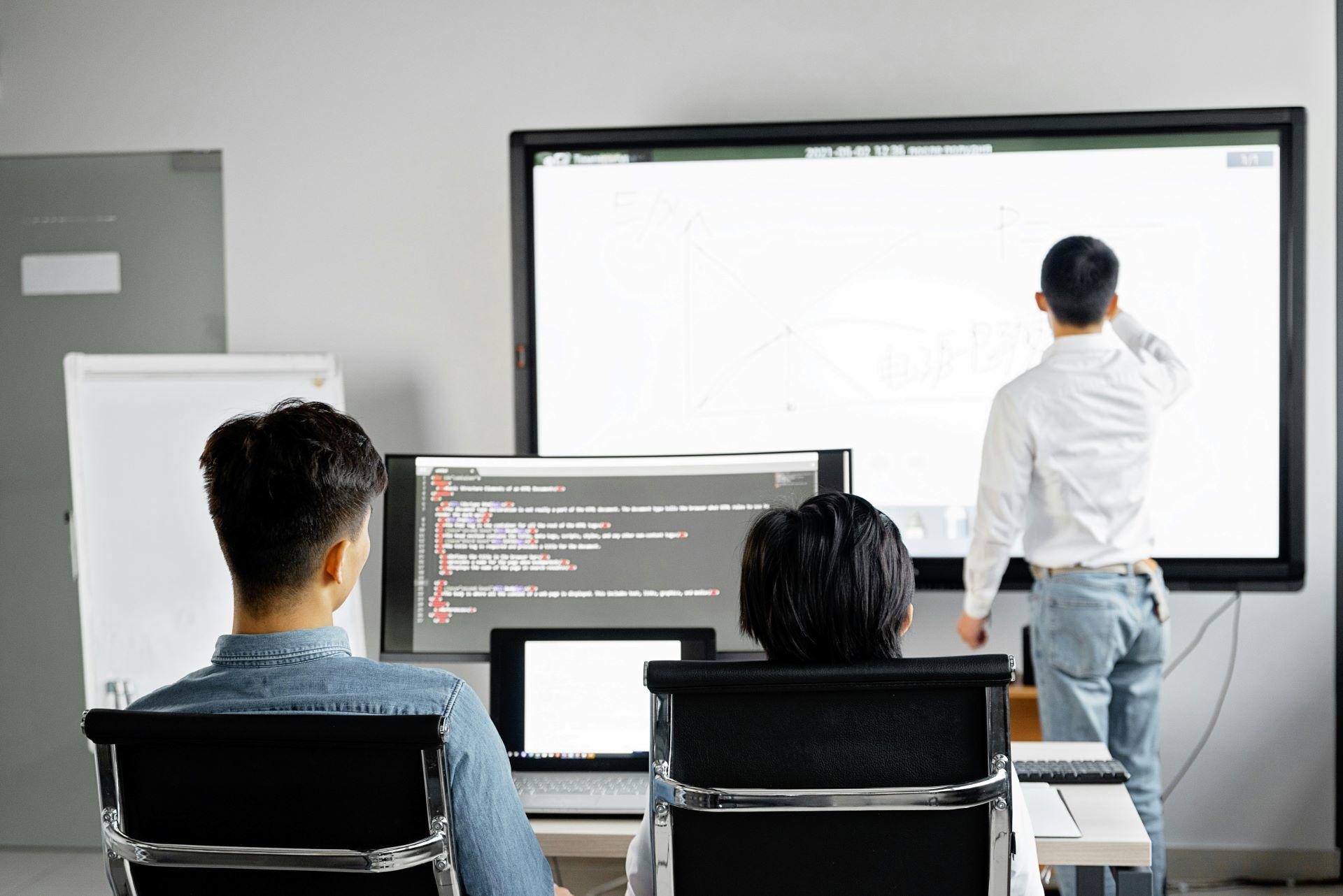 Two students engaged in a discussion with an instructor.