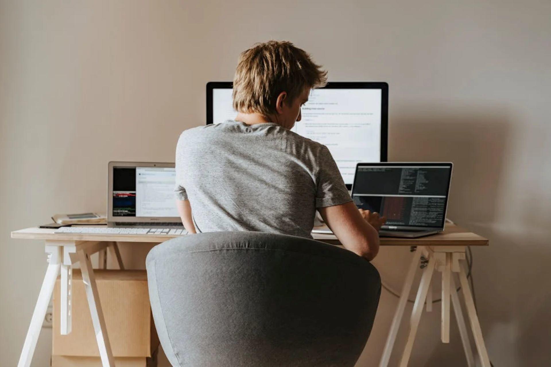 Programmer working from home, coding on a multi-monitor setup.