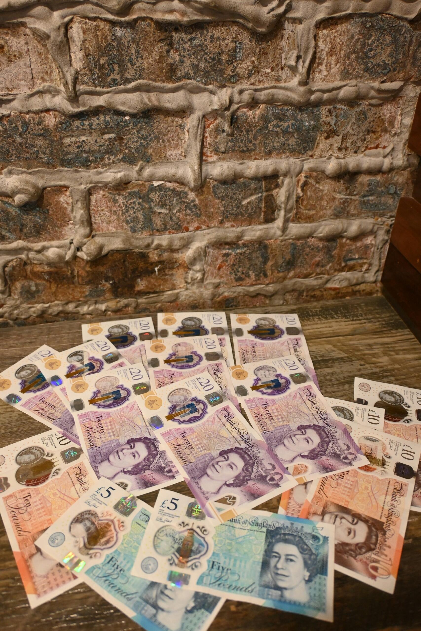 Pound sterling notes laid out on a wooden table.