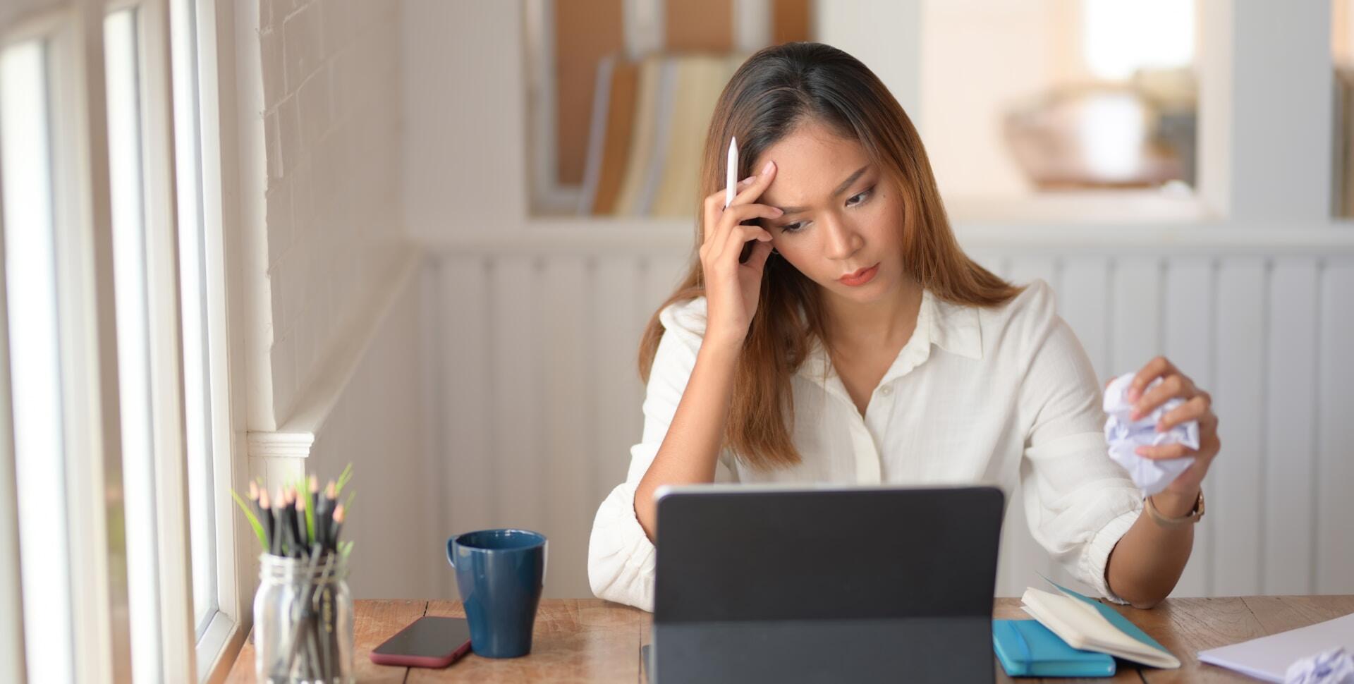 A woman in front of a computer looking worried.