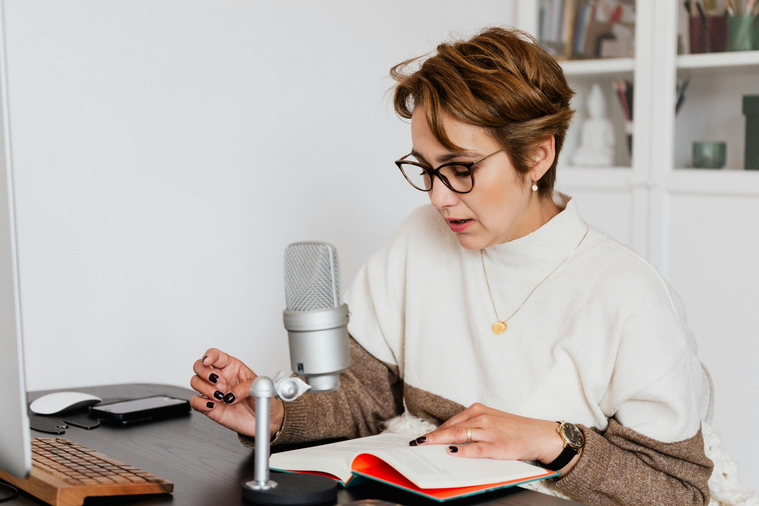 Person sitting at a desk with a microphone and a notebook