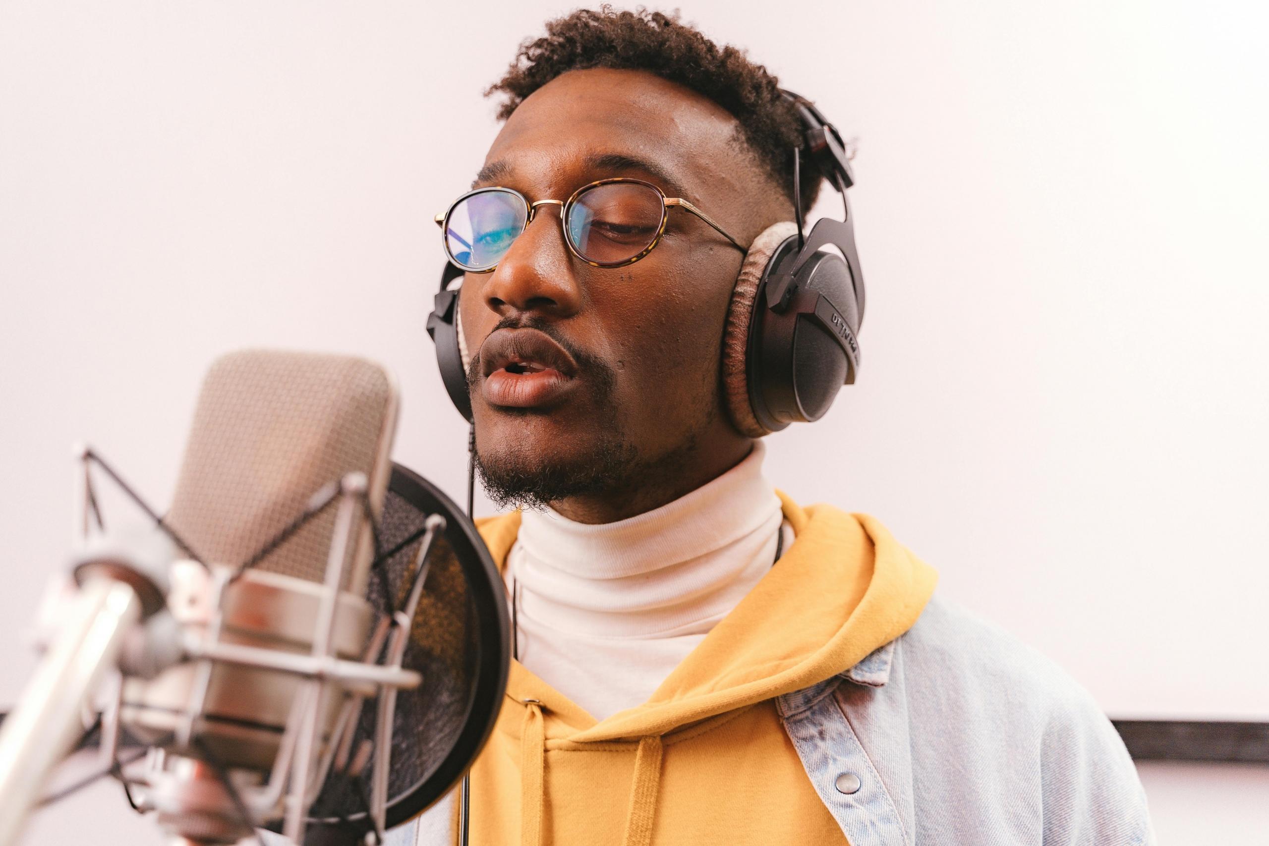 A man with glasses performing in a studio.