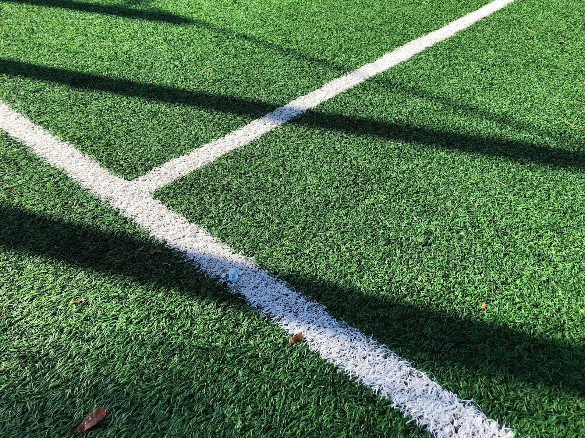 A white line on a green grass field, with another line running perpendicular. 