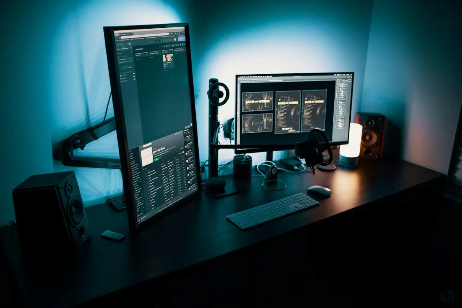Desktop computer setup with two monitors, keyboard, mouse, and design tools.