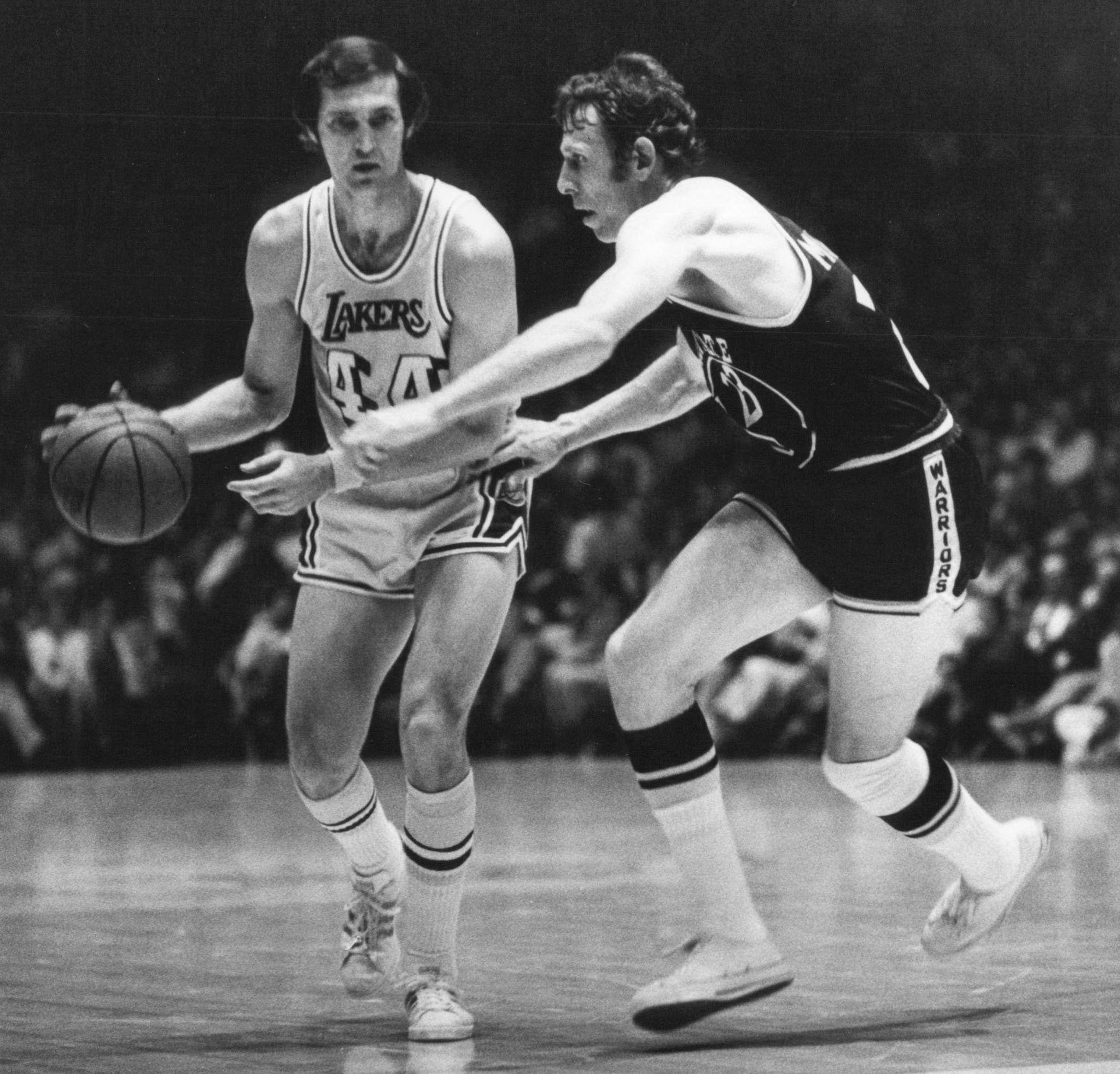 Black and white photo of Jerry West dribbling through an opponent.