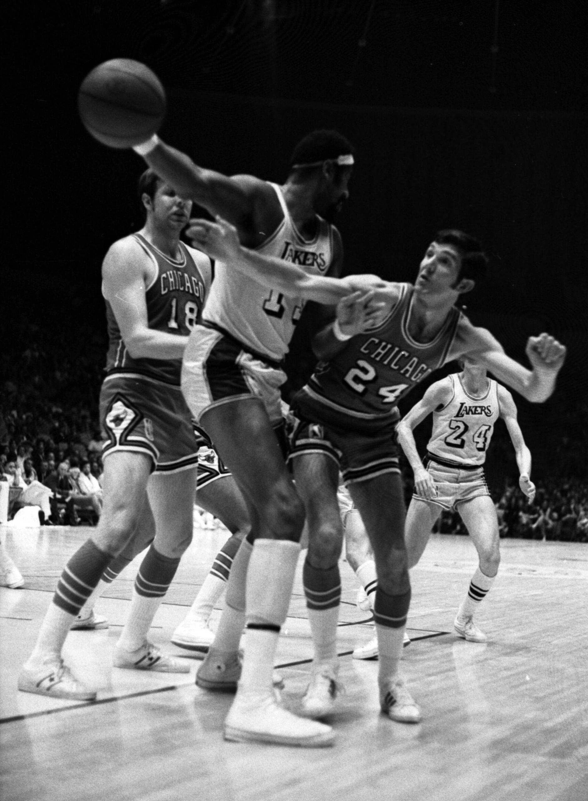 Black and white photo of Chamberlain against two basketball opponents.
