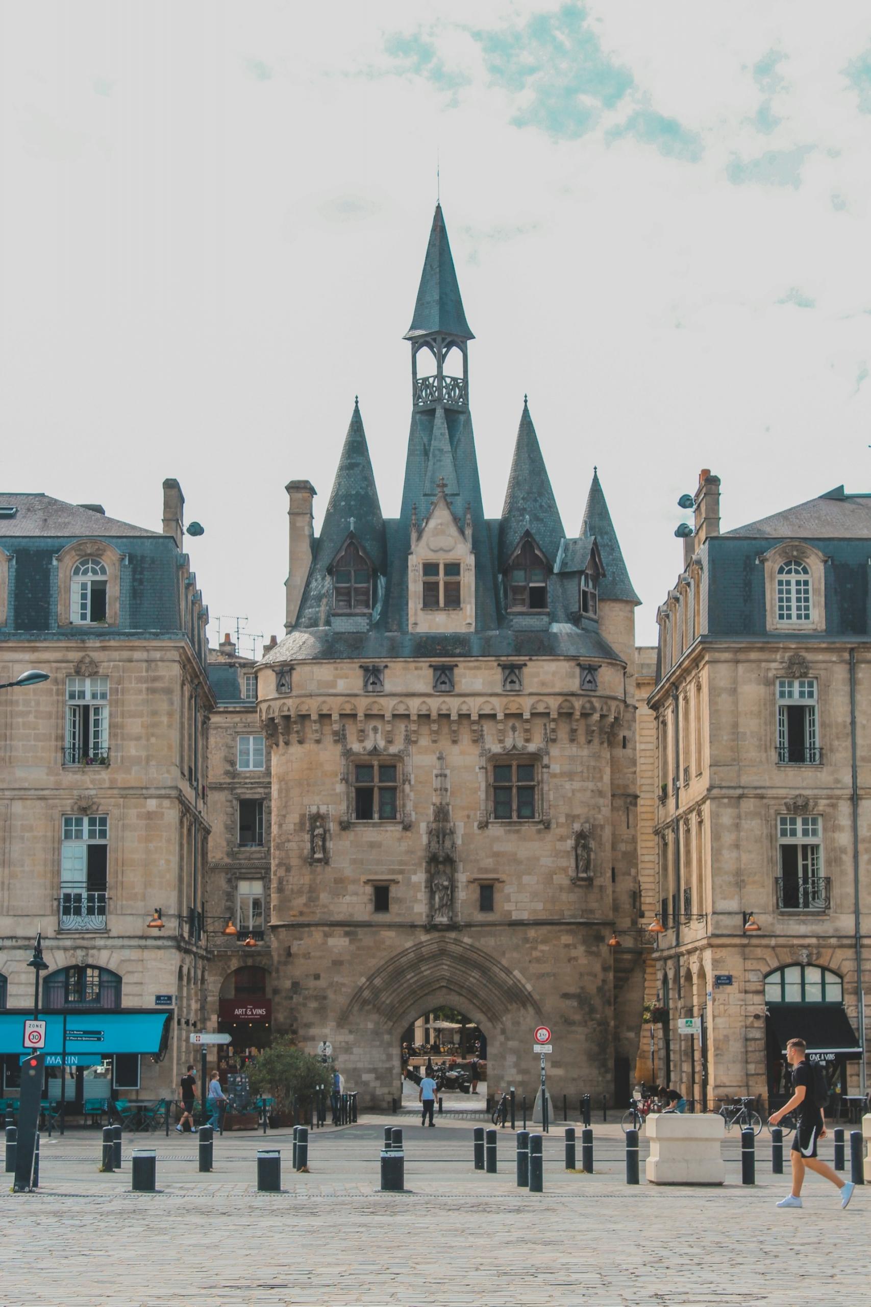 A medieval stone gate flanked by other buildings. 