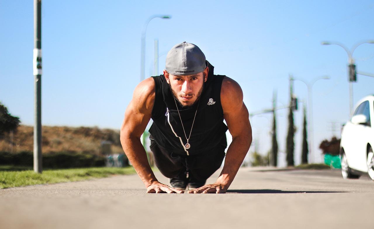 A man doing a push-up in the middle of a passage way as part of his calisthenics workout plan.
