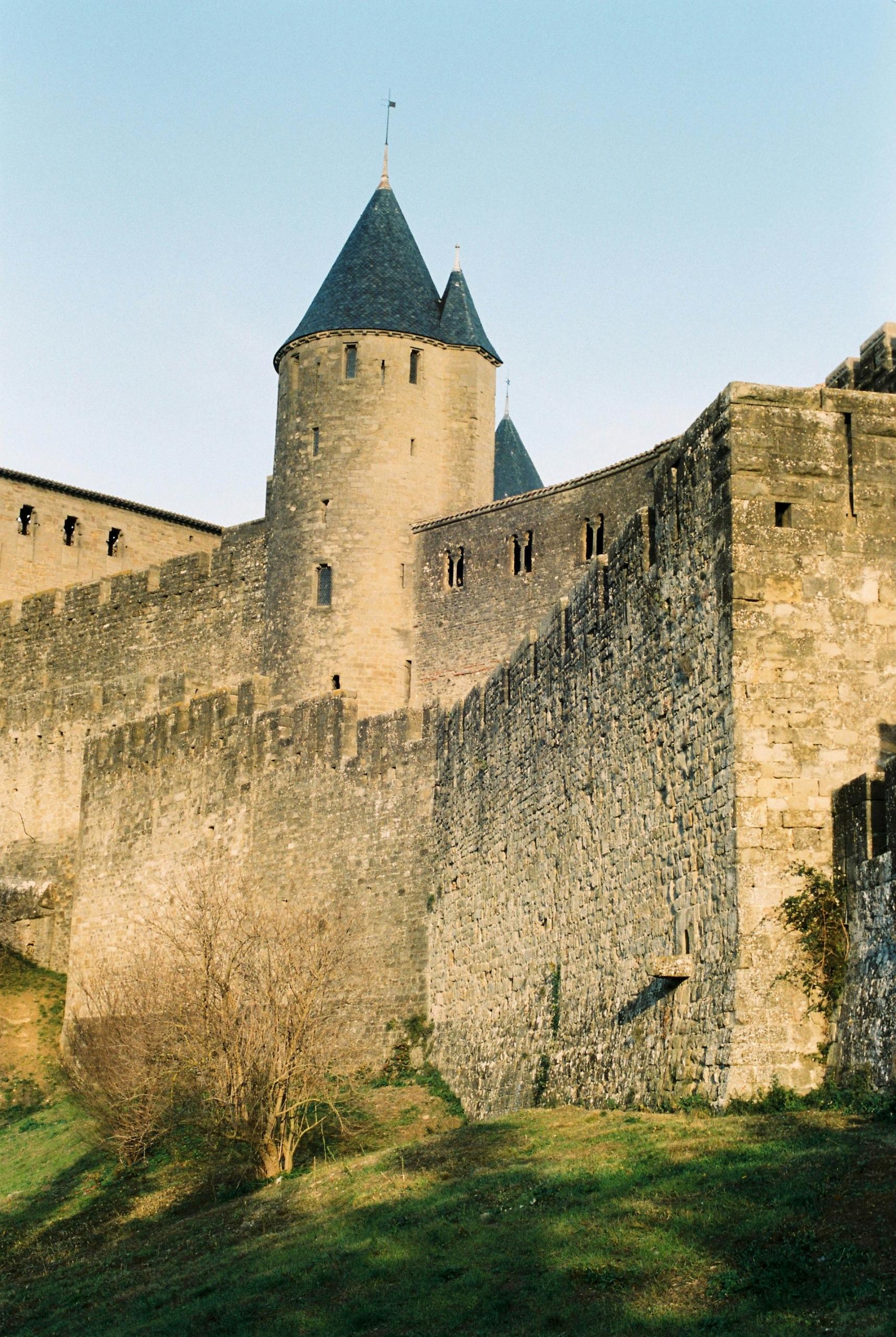 A stone fortress with a black turreted roof in the daytime.