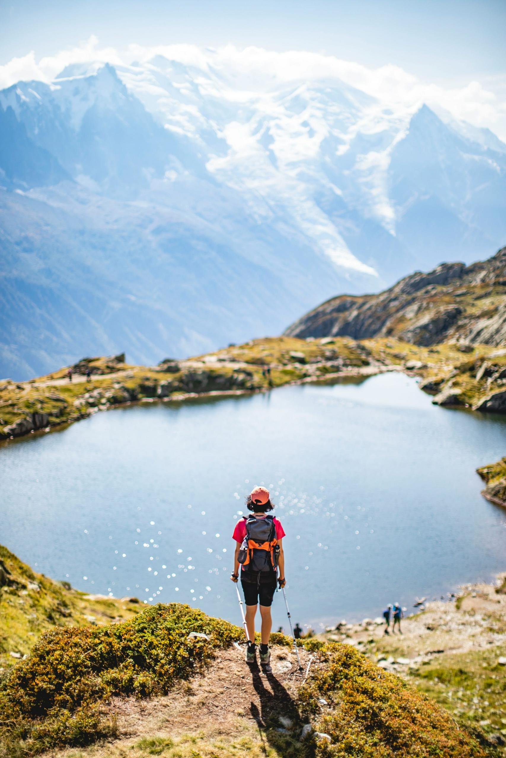 A person stands in front of a small pool atop a mountain. 