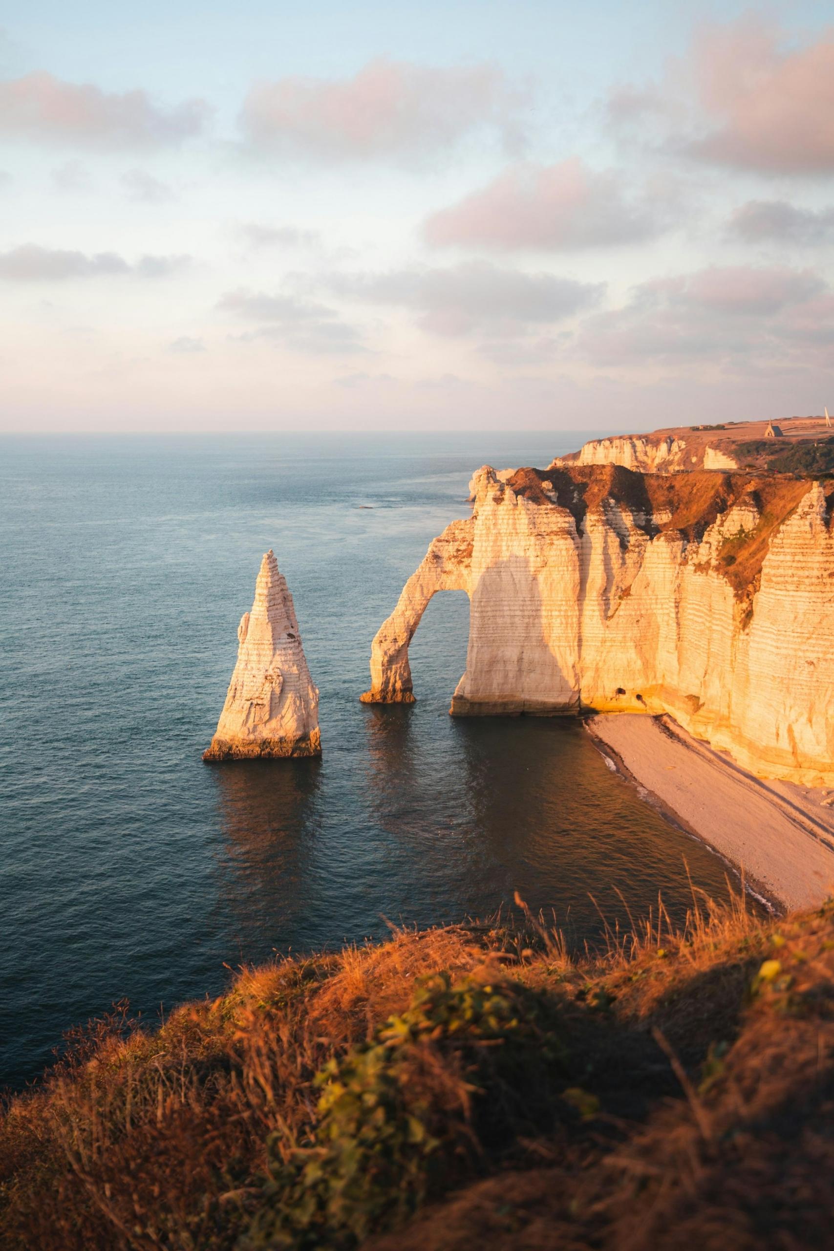A stone arch with needle in water at sunset. 