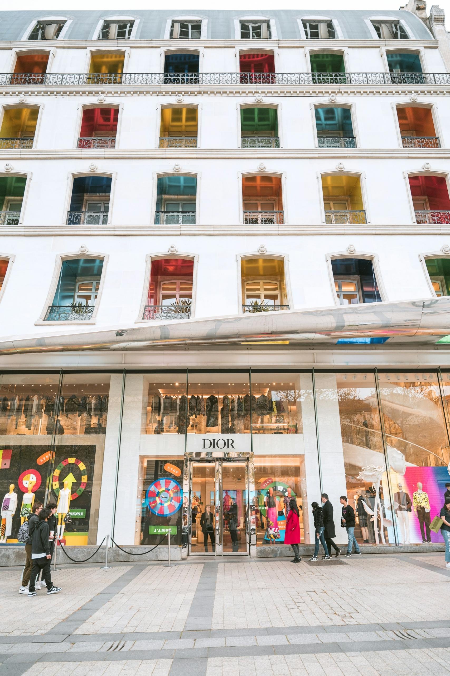 A white building with colourful windows and a shop at ground level. 