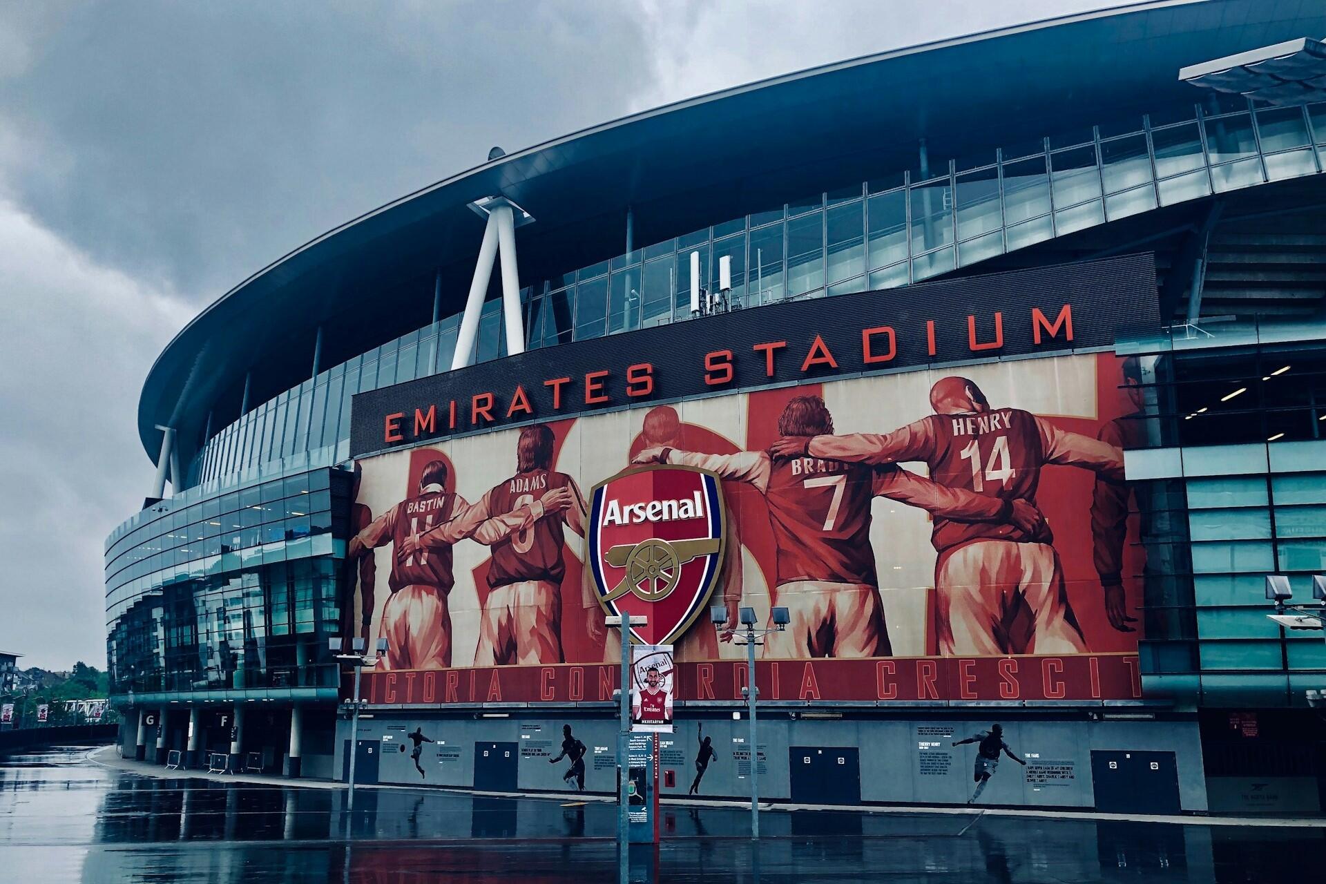 Exterior view of Emirates Stadium with the Arsenal crest and player mural on the front of the building