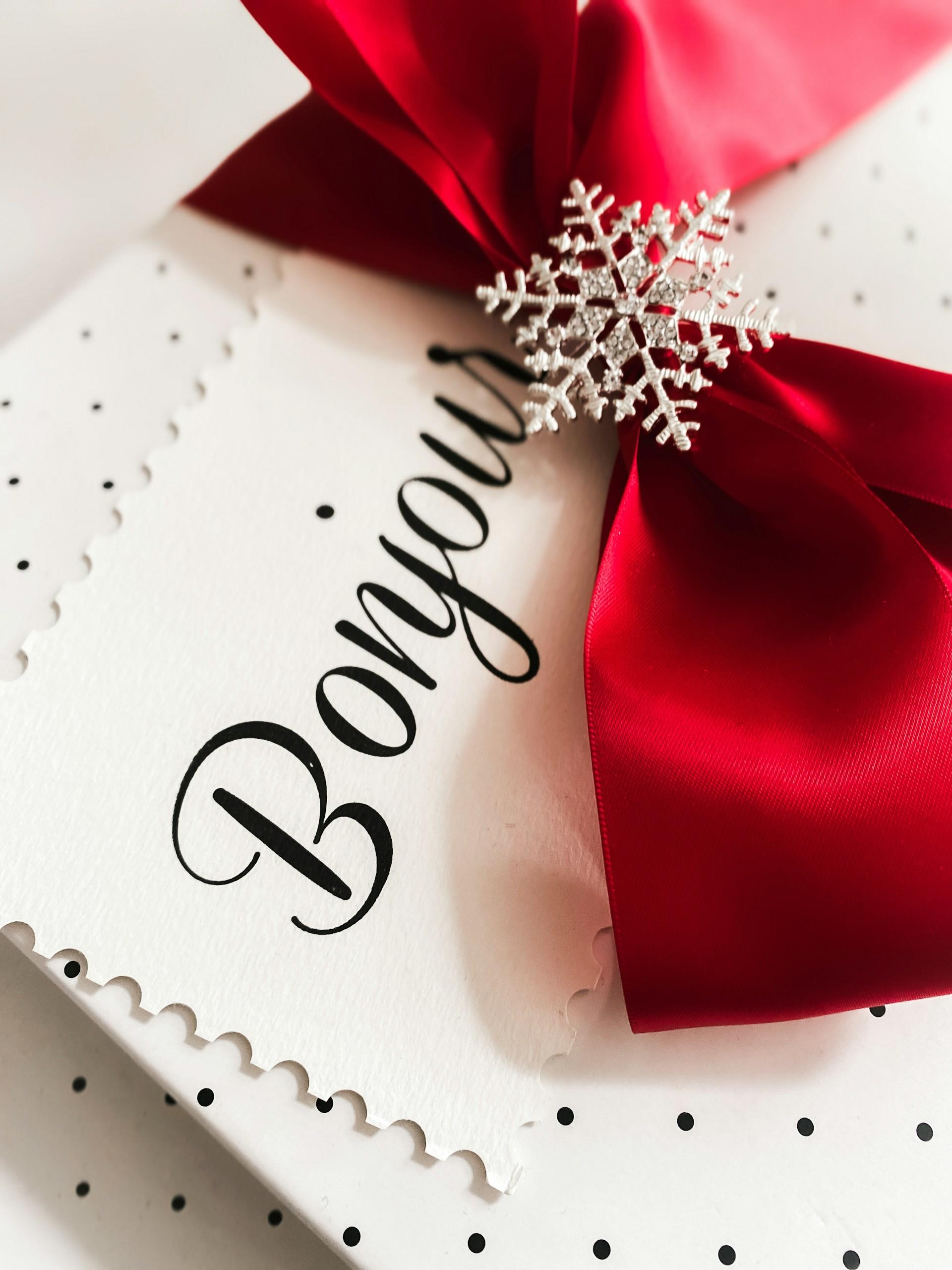 A greeting card with a keep red ribbon lying atop it.