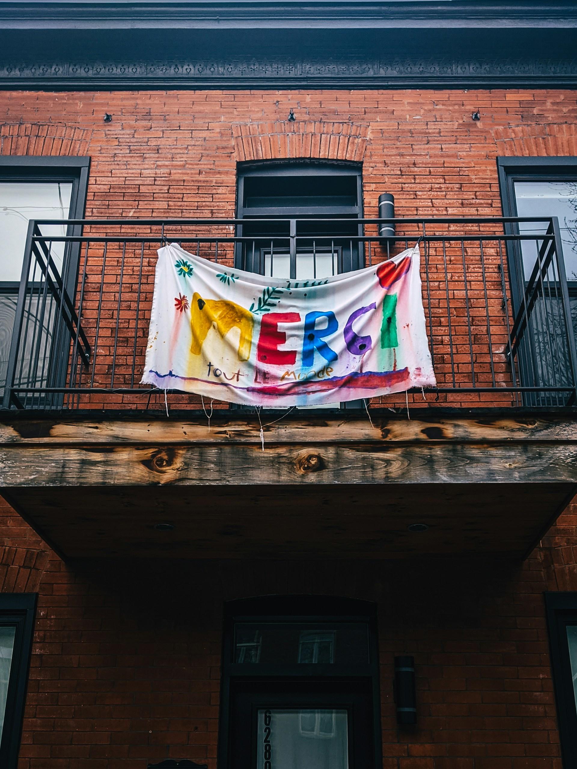 A French word painted on a white banner hanging on a balcony railing. 