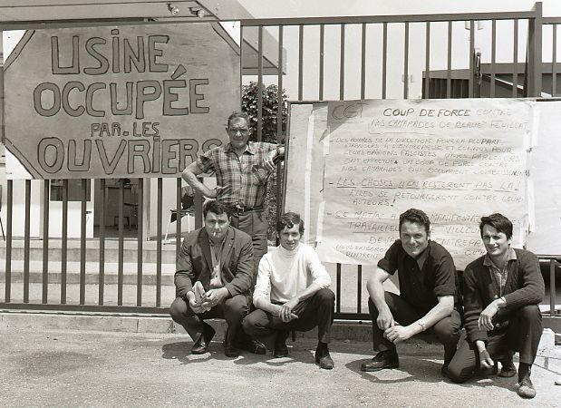 A photograph of five workers outside their factory in the south of France, with a sign reading "Factory Occupied by the Workers."