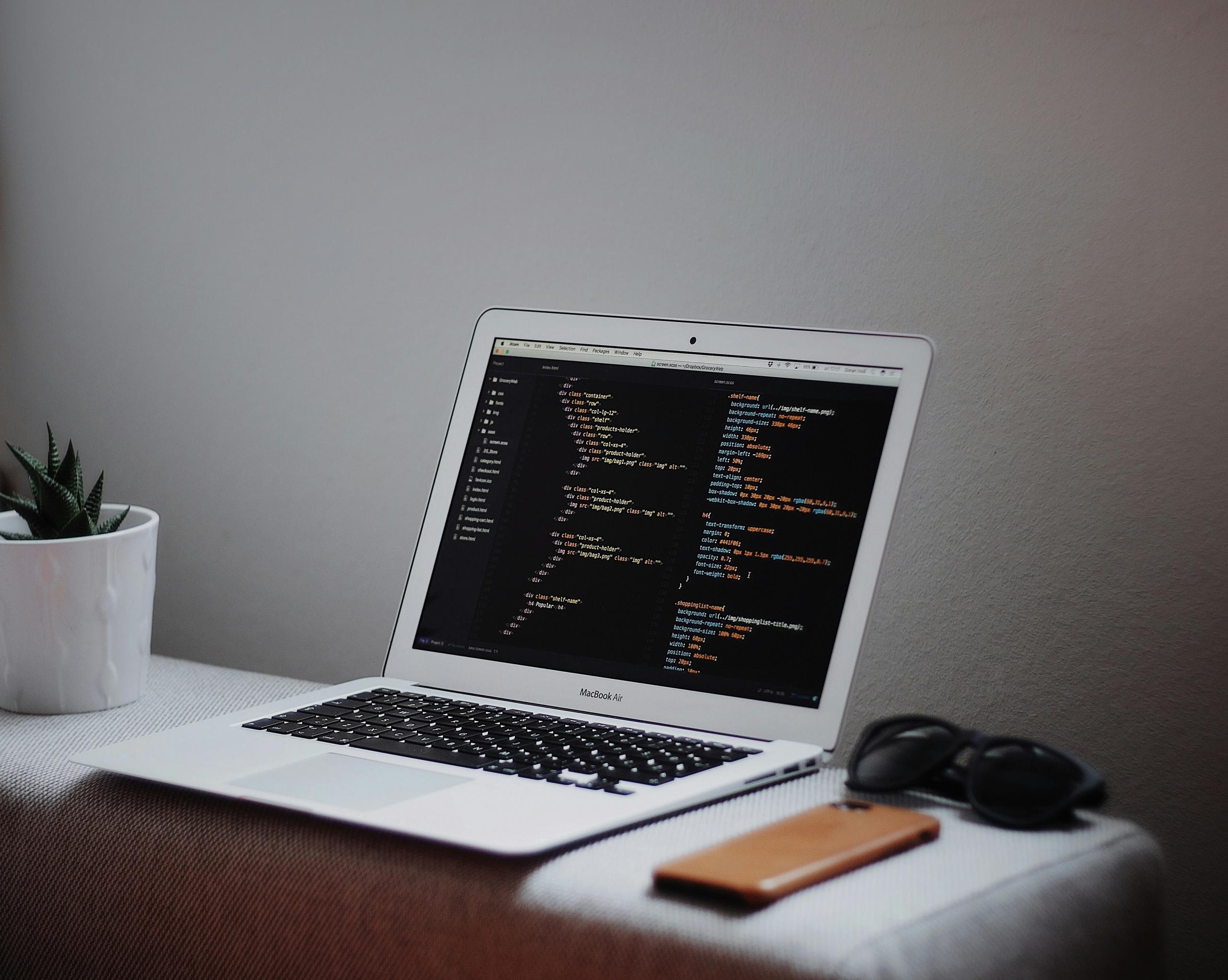 A laptop on the table with coding on it's screen
