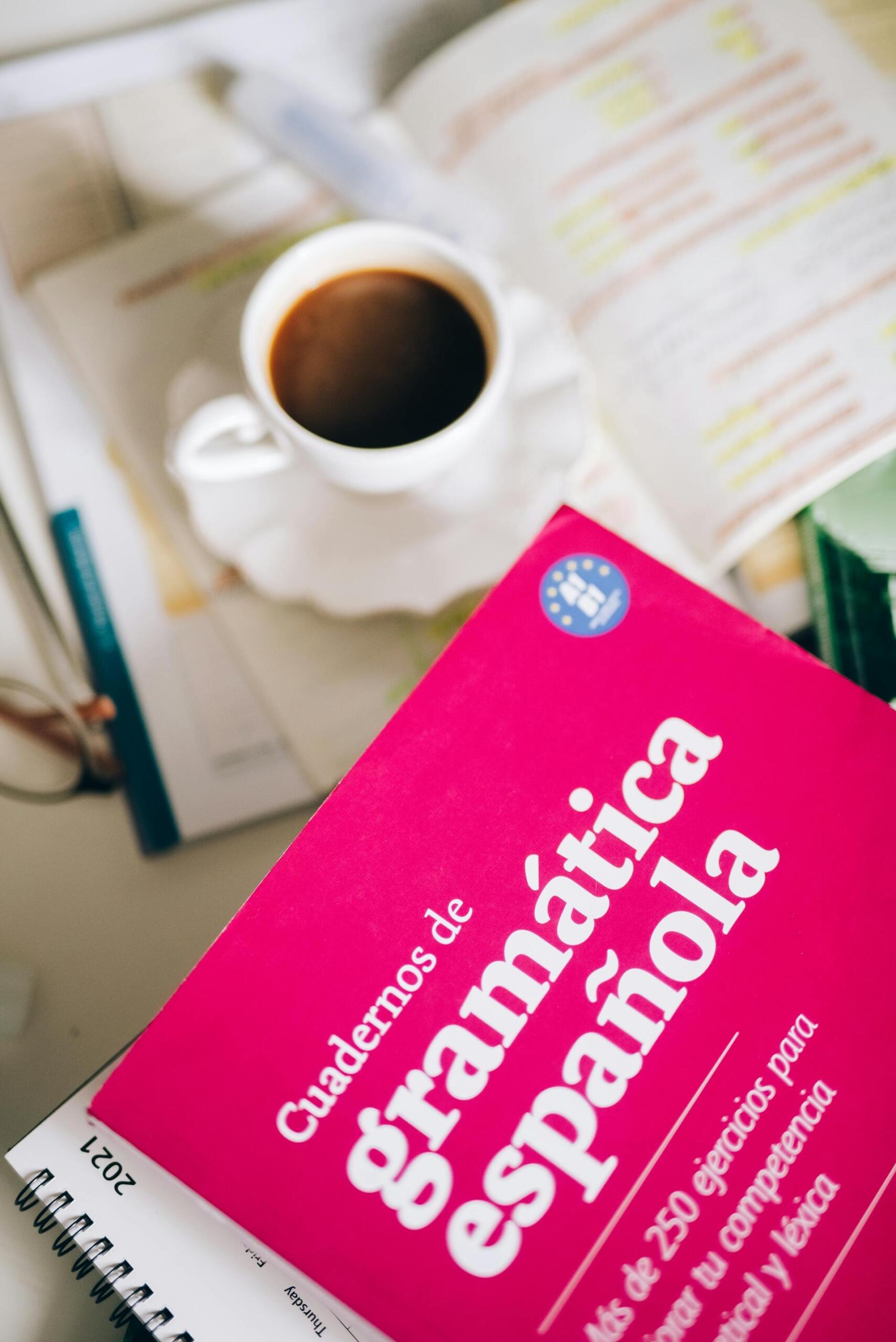 A cup of coffee and an open Spanish book with the title “Gramatica Espanola”.