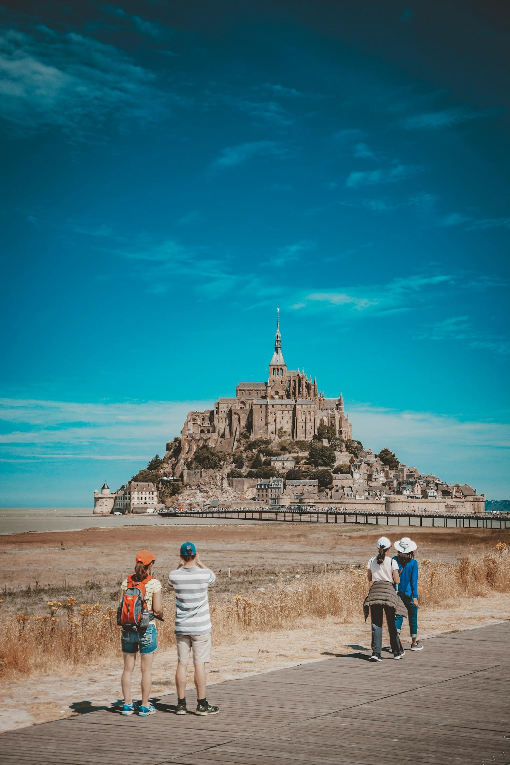 A distant structure against a blue sky with people in the foreground.