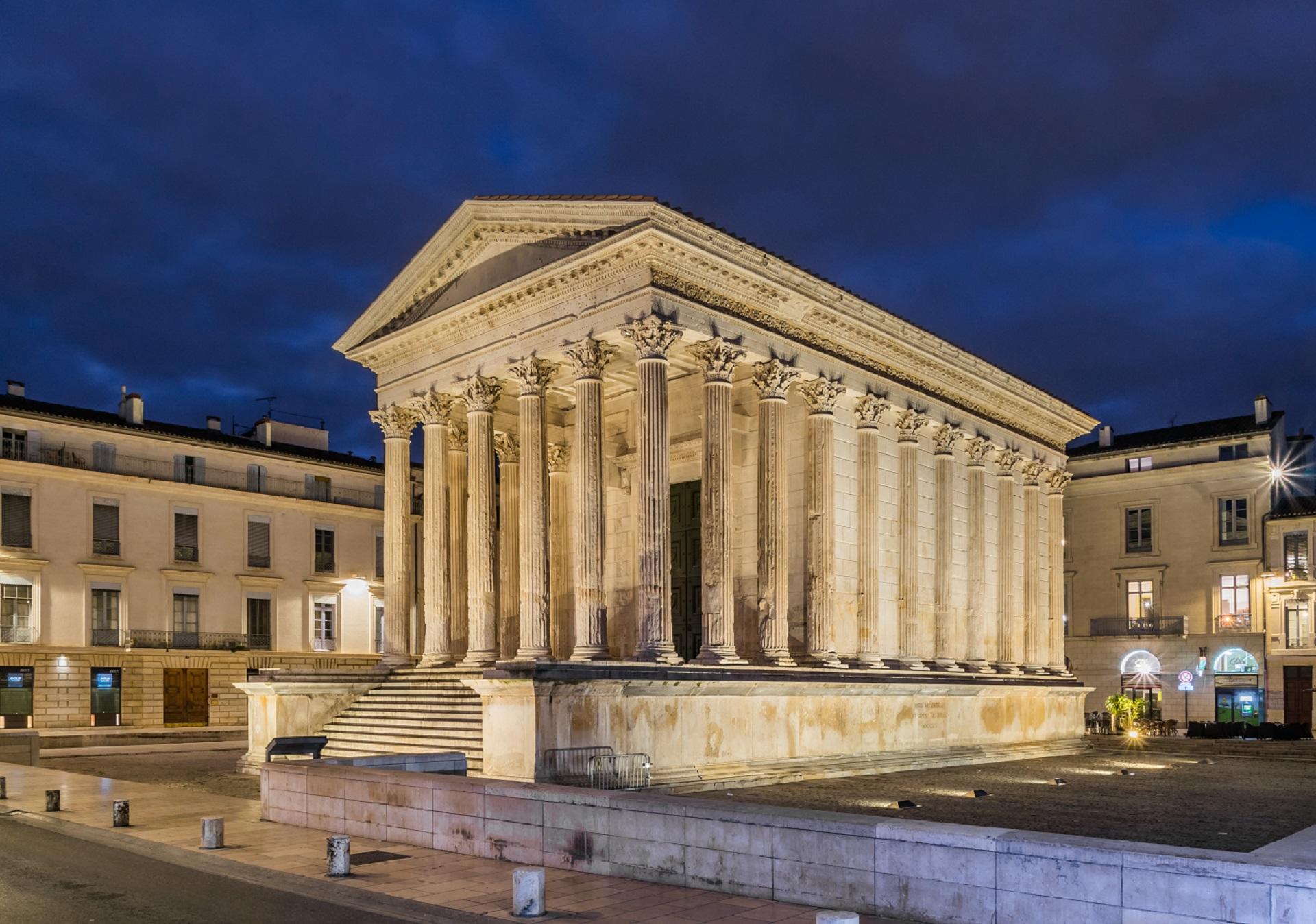 A white stone building with columns lit up at night.