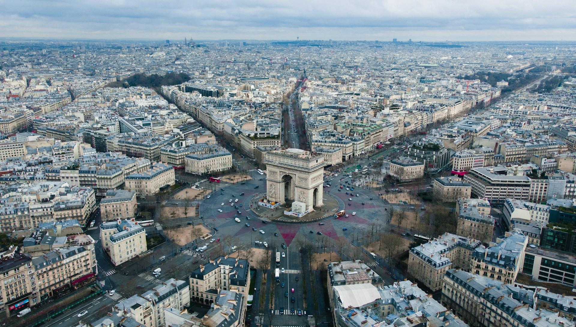 A bird's eye view of the Paris arch and radiating roads on an overcast day.