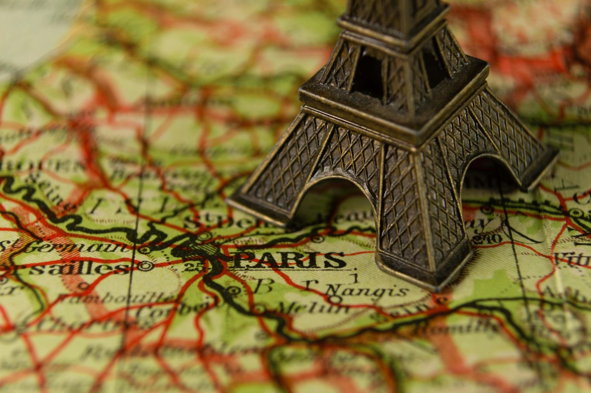 A green map with red lines and a miniature Eiffel tower on it.