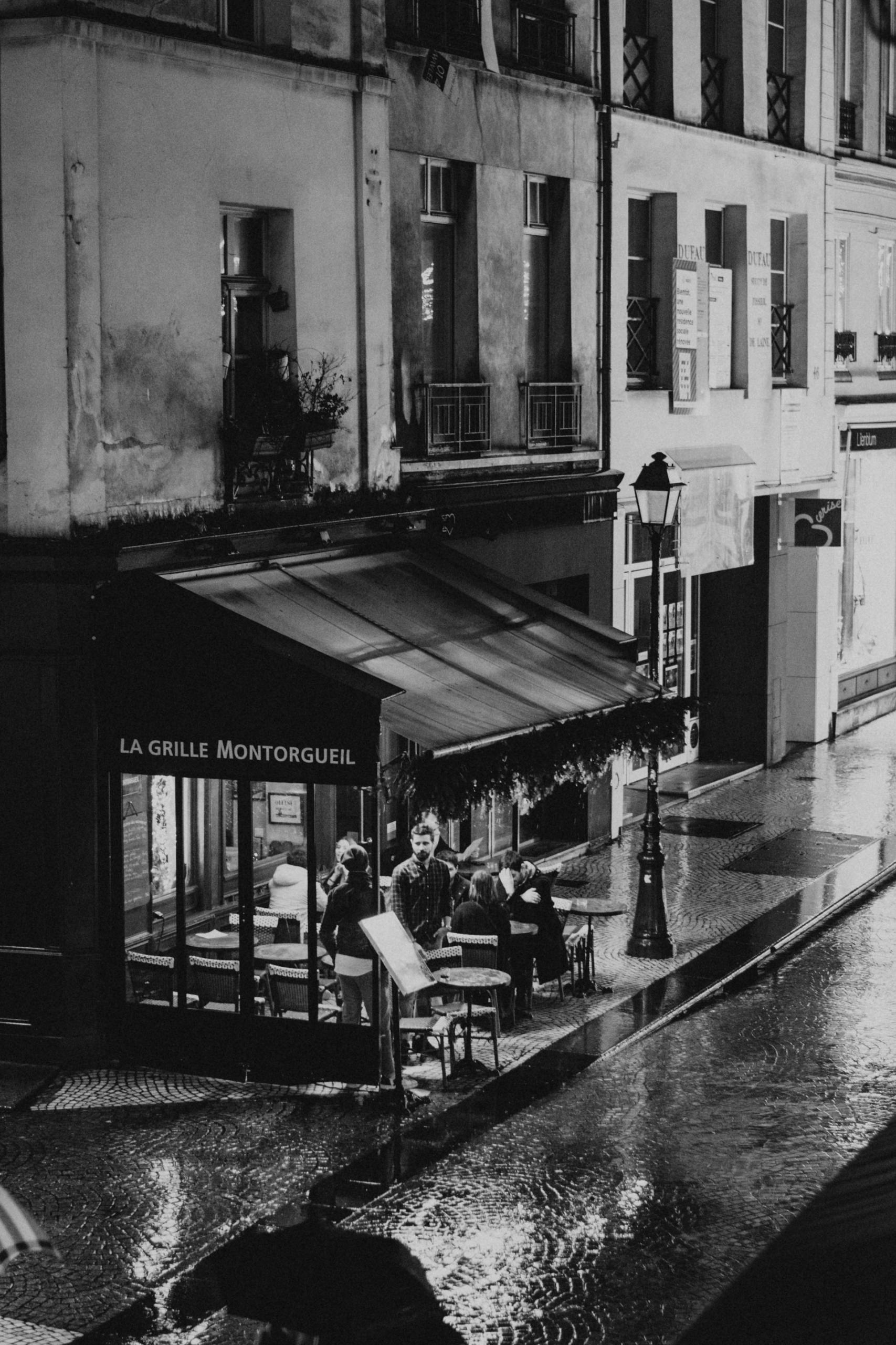 A greyscale image of a restaurant awning on a rainy night. 