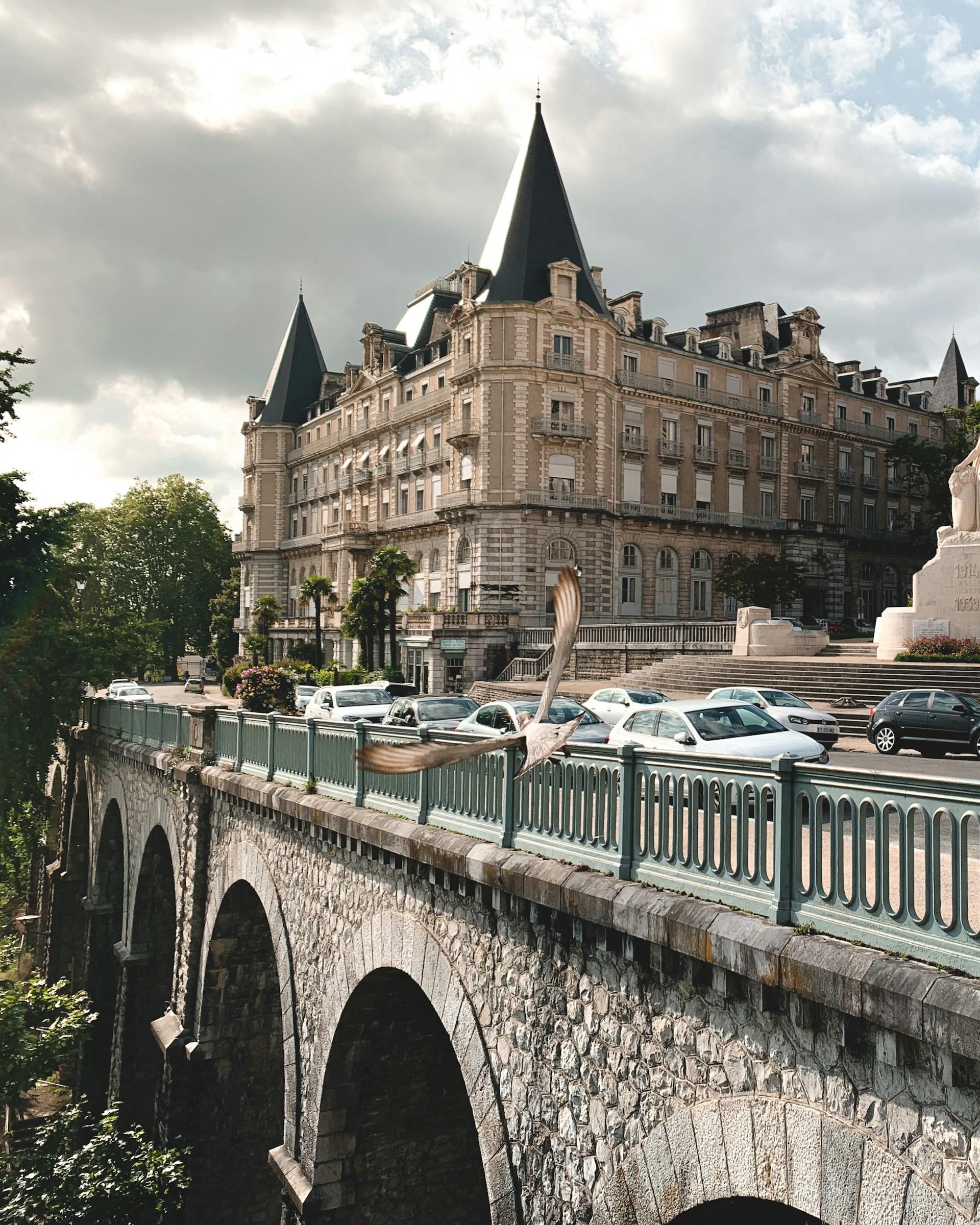 A stone bridge with a large building in the background.
